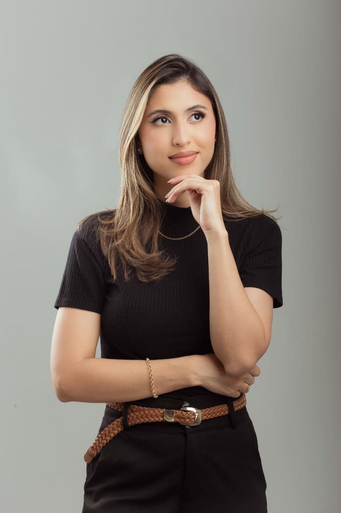 Retrato da Dra. Juliana Rodrigues de blusa preta, com a mão no queixo